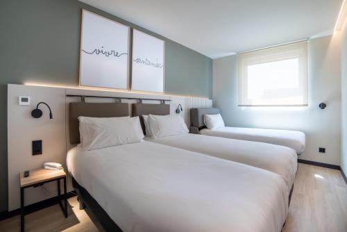 two beds in a hotel room with white sheets at ibis Styles Santander in Santander