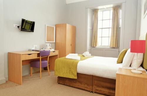a bedroom with a bed and a desk with a computer at The Portpatrick Hotel by Compass Hospitality in Portpatrick