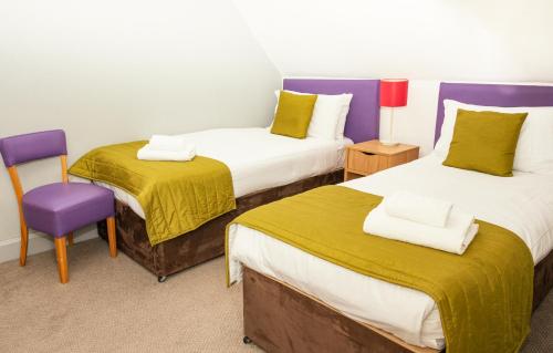 a room with two beds and a purple chair at The Portpatrick Hotel by Compass Hospitality in Portpatrick