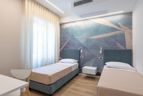 two beds in a room with a painting on the wall at Albergo Degli Amici in Chieti