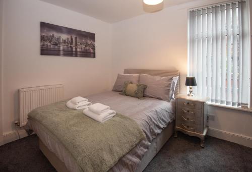 a bedroom with a bed with two towels on it at Cross Street by Prestige Properties SA in Barrow in Furness