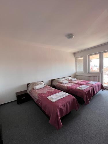 two beds in a room with red sheets at Hotel Begić in Sarajevo