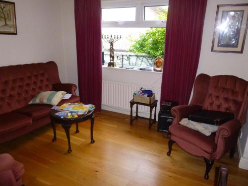 a living room with two chairs and a table and a window at Dun Roamin in Galway