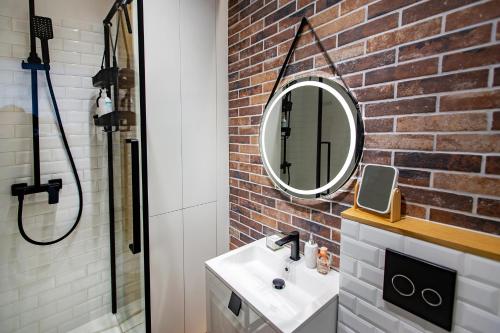 ein Badezimmer mit einem weißen Waschbecken und einer Ziegelwand in der Unterkunft Hillside7 Micro-Loft in Bielsko-Biała