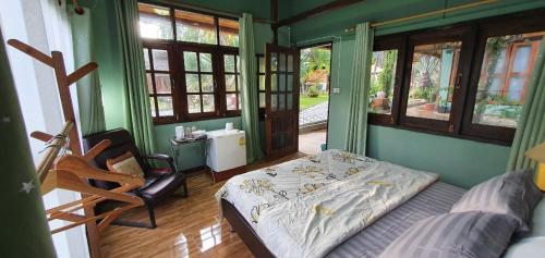 a bedroom with a bed and a chair in it at Baan Suan Taboon Homestay in Chiang Rai