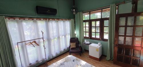 a room with green walls and windows with a television at Baan Suan Taboon Homestay in Chiang Rai