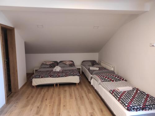 three beds in a room with wooden floors at Pension Imlauf in Vrchlabí