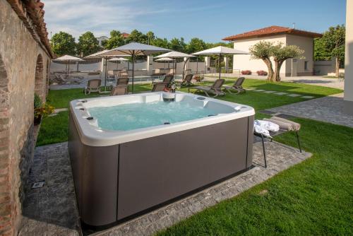 a hot tub in a yard with chairs and umbrellas at VILLA BERNASCONI in Narzole
