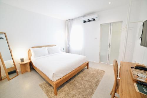 a white bedroom with a bed and a mirror at Evergreen Cafe and Hotel in Chiang Mai
