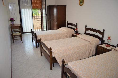 Zimmer mit 3 Betten, Tisch und Stühlen in der Unterkunft Domus Achille Fosco in Ciampino