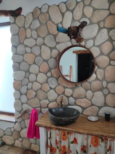 a bathroom with a sink and a mirror on a stone wall at El molino del abuelo in Montecorto