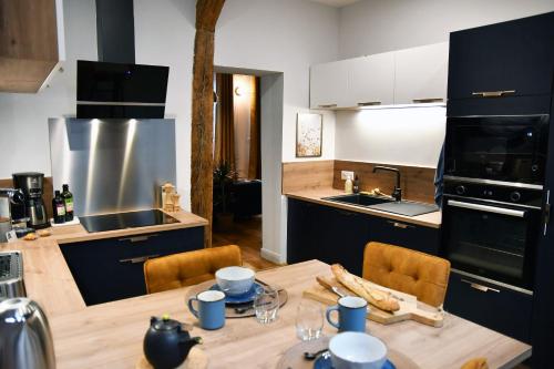 une cuisine avec une table en bois et des chaises et une cuisine avec un évier dans l'établissement L'escale du Gros Horloge, à Rouen