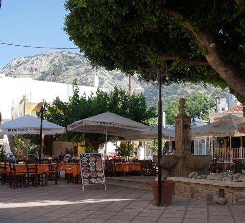 an outdoor cafe with tables and umbrellas and chairs at Lotza Traditional House Salakos in Sálakos