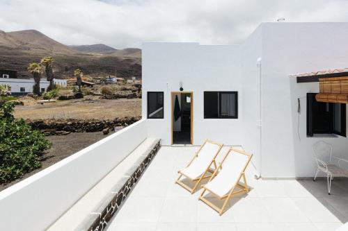 a white house with two chairs on the balcony at La Casa de La Caleta by Taller96 - El Hierro Island - in La Caleta