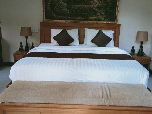 a bedroom with a large white bed with two lamps at The oasis retreat seminyak in Seminyak