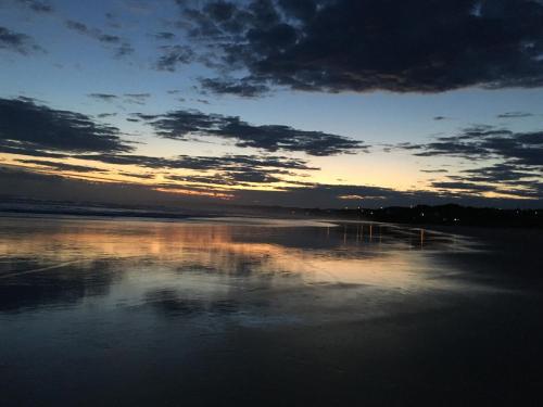 a sunset over a body of water with clouds at Stay in School by the Sea in Dunedin