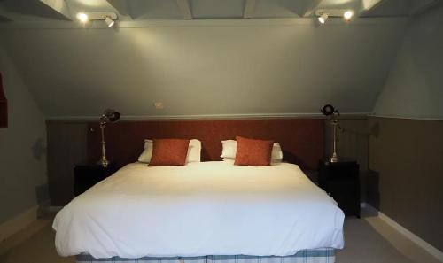 a bedroom with a large white bed with red pillows at The Fiddichside Inn in Aberlour