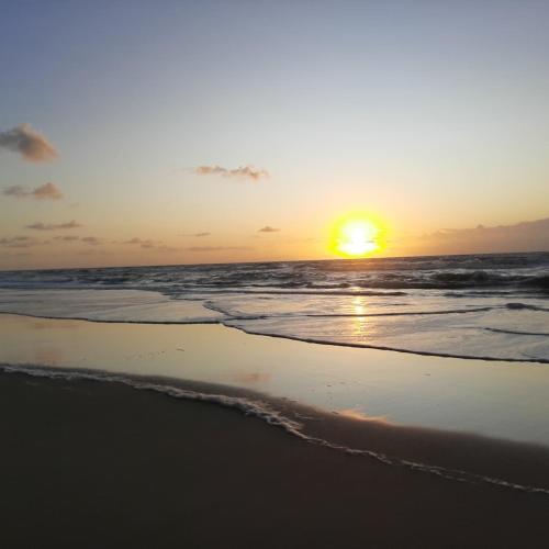 a sunset on the beach with the ocean at Pousada Hawai in Conde