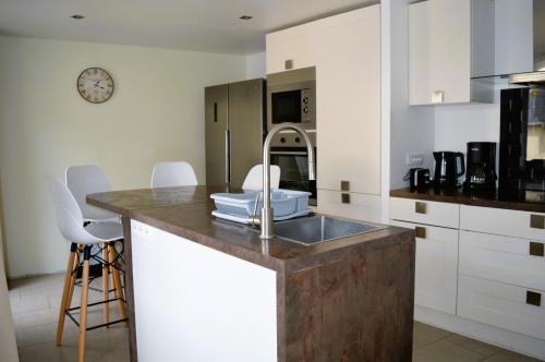 - une cuisine avec un évier et des placards blancs dans l'établissement Halte Lutine - Maison chaleureuse en pierres, à Luc-sur-Mer
