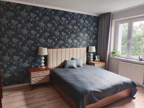 1 dormitorio con cama y papel pintado con motivos florales en Apartament, en Gdansk