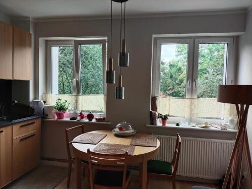 cocina con mesa y sillas y 2 ventanas en Apartament, en Gdansk