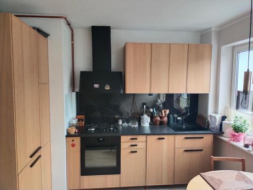 a kitchen with wooden cabinets and a black stove at Apartament in Gdańsk