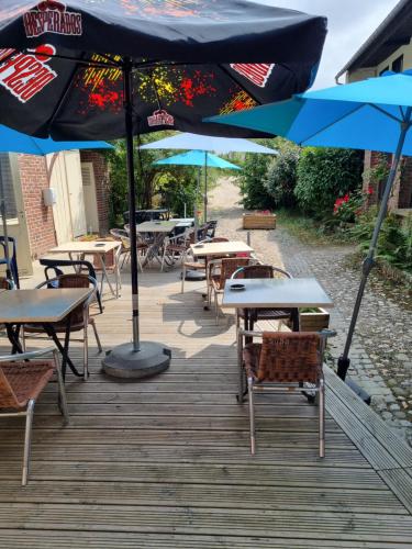 un groupe de tables et de parapluies sur une terrasse dans l'établissement hotel du commerce, à Fauville-en-Caux