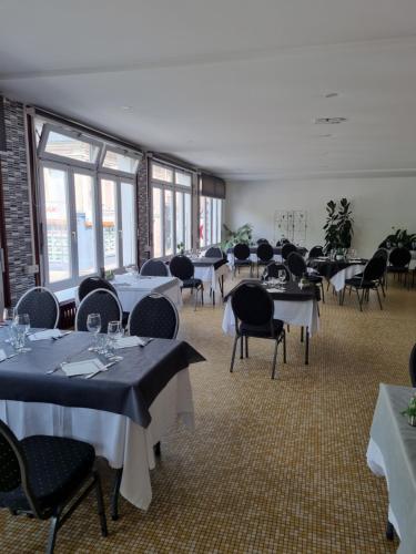 ein Esszimmer mit Tischen, Stühlen und Fenstern in der Unterkunft hotel du commerce in Fauville-en-Caux