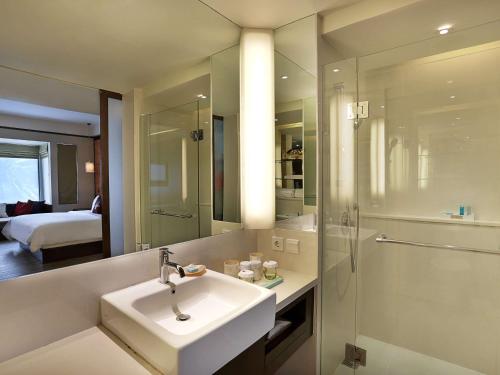 a bathroom with a sink, mirror, and bathtub at Novotel Lombok Resort & Villas in Kuta Lombok
