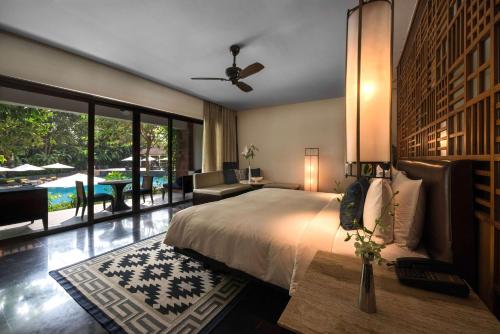 Diwa Club by Alila - A Hyatt Brand في ماجوردا: غرفة نوم بسرير وإطلالة على المسبح