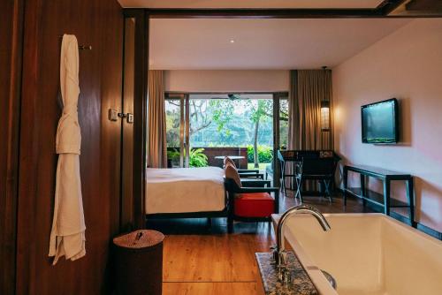 a bathroom with a tub and a bedroom with a bed at Alila Diwa Goa - A Hyatt Brand in Majorda