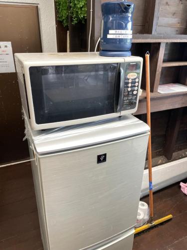 um micro-ondas sentado em cima de um frigorífico em ゲストハウス303 em Zamami