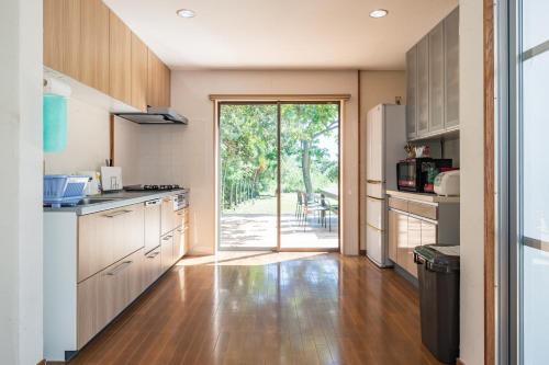 a kitchen with wooden cabinets and a door to a patio at Palm Villa Ishigakijima igusa in Ishigaki Island