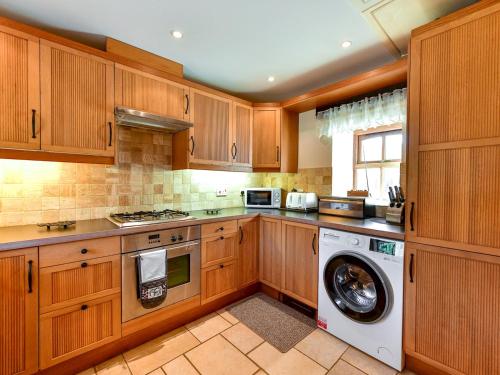 a kitchen with wooden cabinets and a washer and dryer at Pass the Keys Cosy Rural 2 Bed Barn conversion close to Beach in Marcross