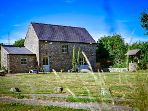 a stone cottage with a grassy yard in front of it at Pass the Keys Cosy Rural 2 Bed Barn conversion close to Beach in Marcross