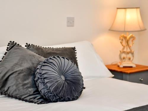 a bed with black and grey pillows and a lamp at Pass the Keys Cosy Rural 2 Bed Barn conversion close to Beach in Marcross