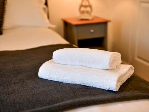 two towels are stacked on top of a bed at Pass the Keys Cosy Rural 2 Bed Barn conversion close to Beach in Marcross