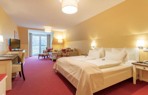 a hotel room with a large bed and a living room at Hotel Landhaus Ellerbrock in Sankt Peter-Ording