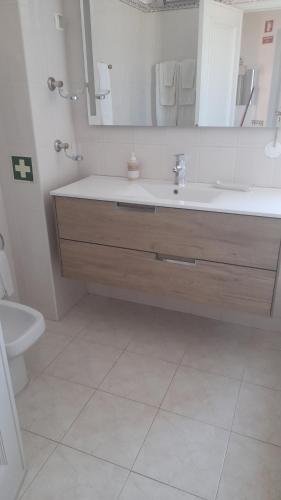 a bathroom with a sink and a toilet and a mirror at A Apartmento Solar dos Pinheiros in Vilamoura