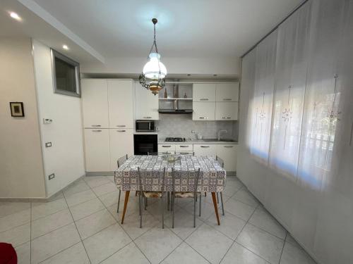 una cucina con tavolo, sedie e lampadario pendente di Casa Milano - Sottomarina a Sottomarina