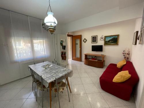 een woonkamer met een rode bank en een tafel bij Casa Milano - Sottomarina in Sottomarina