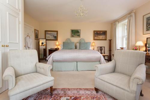 a bedroom with a bed and two chairs at Ingram House Bed & Breakfast in Alnwick