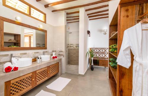 La salle de bains est pourvue de 2 lavabos et d'un miroir. dans l'établissement Zanzibar Queen Hotel, à Matemwe
