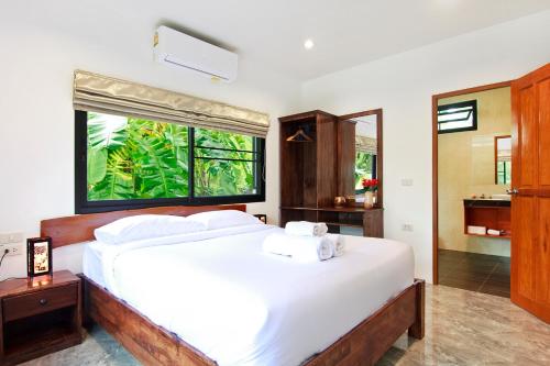a bedroom with a bed with white sheets and a window at 2 Bays Villa in Thong Nai Pan Yai
