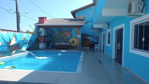 a swimming pool in front of a blue house at Flat's Da Bia in Cananéia