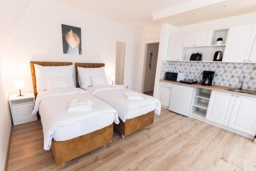 two beds in a room with white walls and wooden floors at Villa Lilith Smart in Fertőrákos