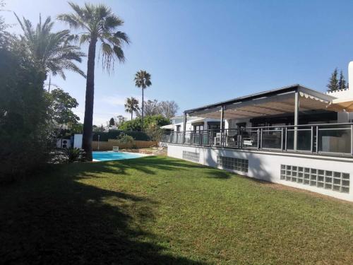 a house with a lawn and palm trees in front of it at Villa Dune, Luxury Villa, 5 min walk to the beach in Marbella