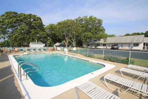 a swimming pool with chairs and a fence at Skaket Beach Motel in Orleans