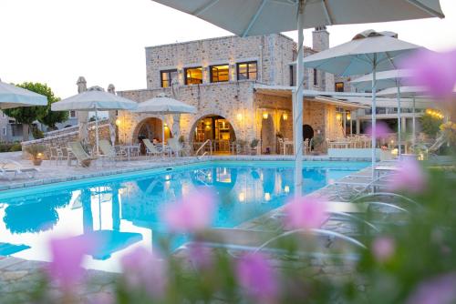 a pool with chairs and umbrellas in front of a building at Castello Antico Hotel in Gythio