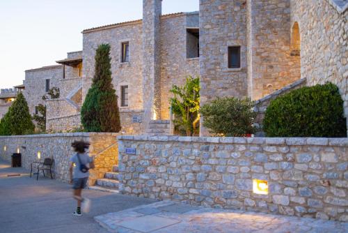 a person walking past a stone wall in front of a building at Castello Antico Hotel in Gythio